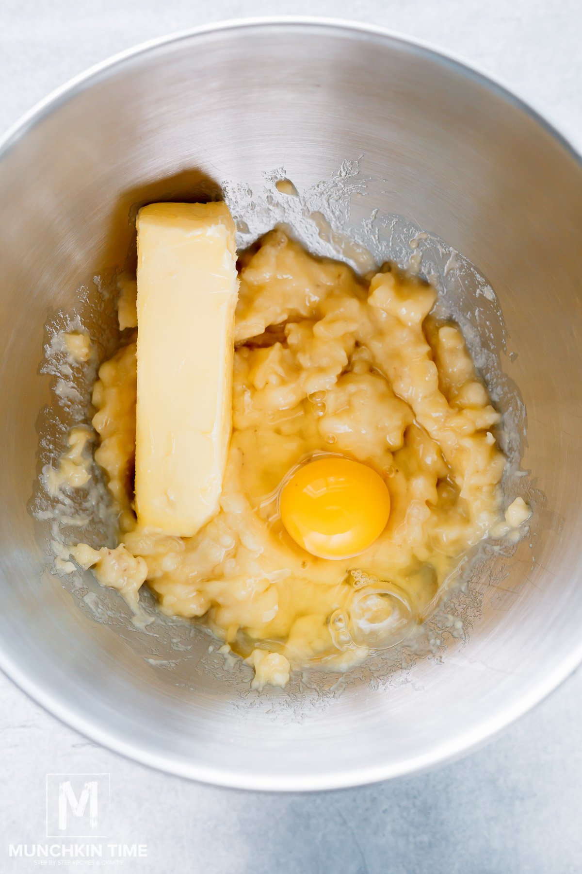 Butter and an egg added to the bowl with mashed bananas.