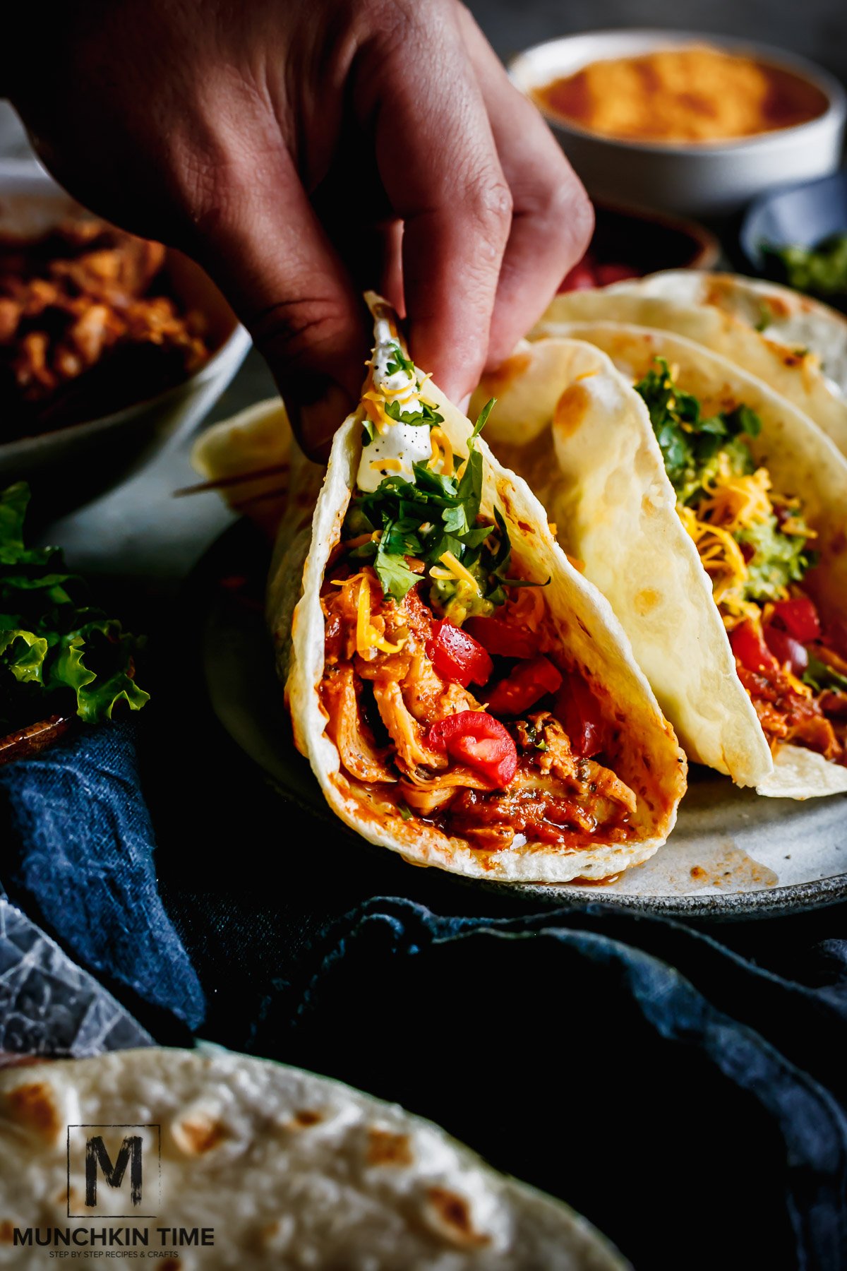 One hand carefully holding warm Chicken Tacos, moving slowly so the shredded chicken juice doesn't escape from the tortilla.