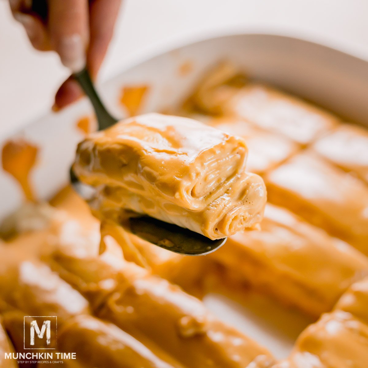 Baked crepes filled with cream on a serving spoon.