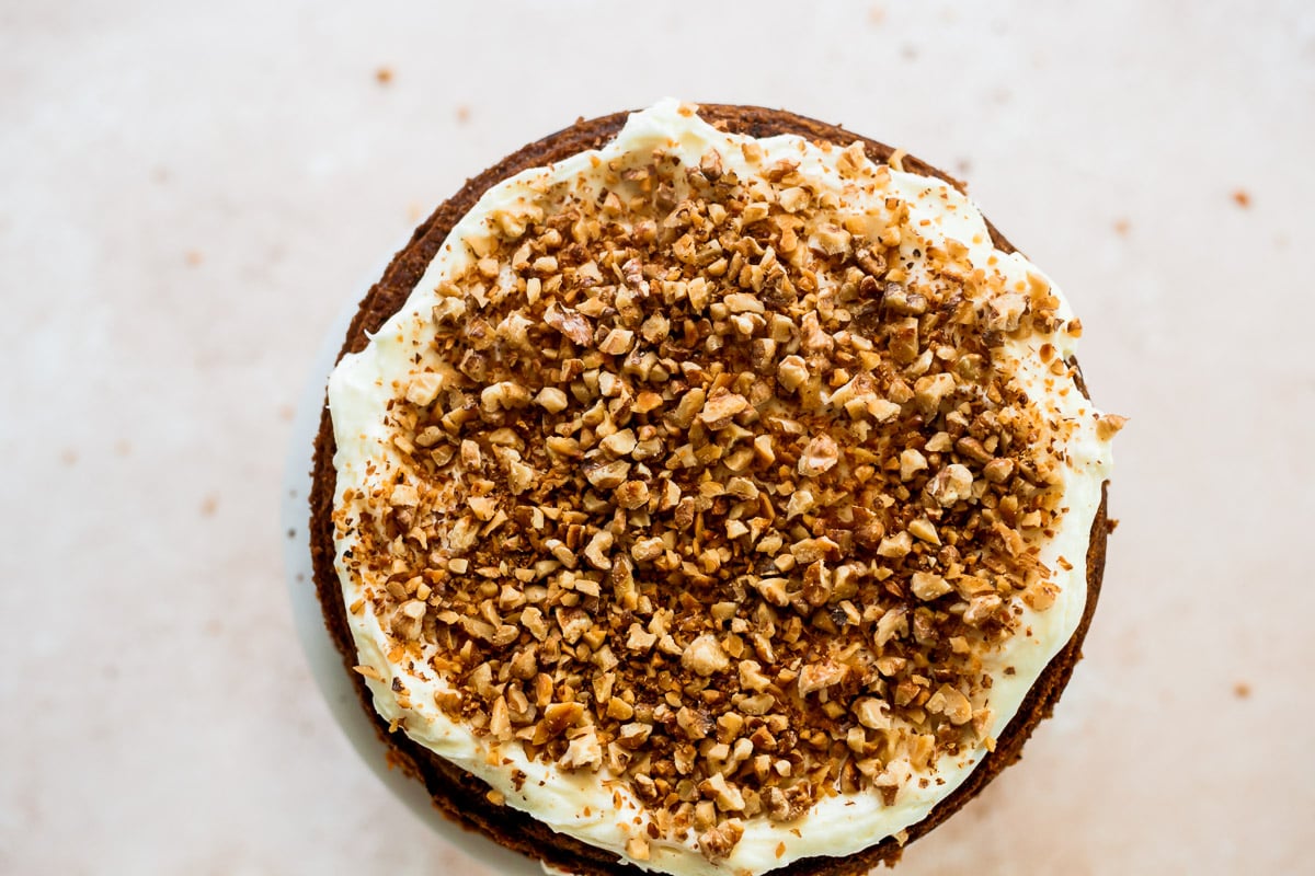 Chopped walnuts added to the cake top over cream cheese frosting .