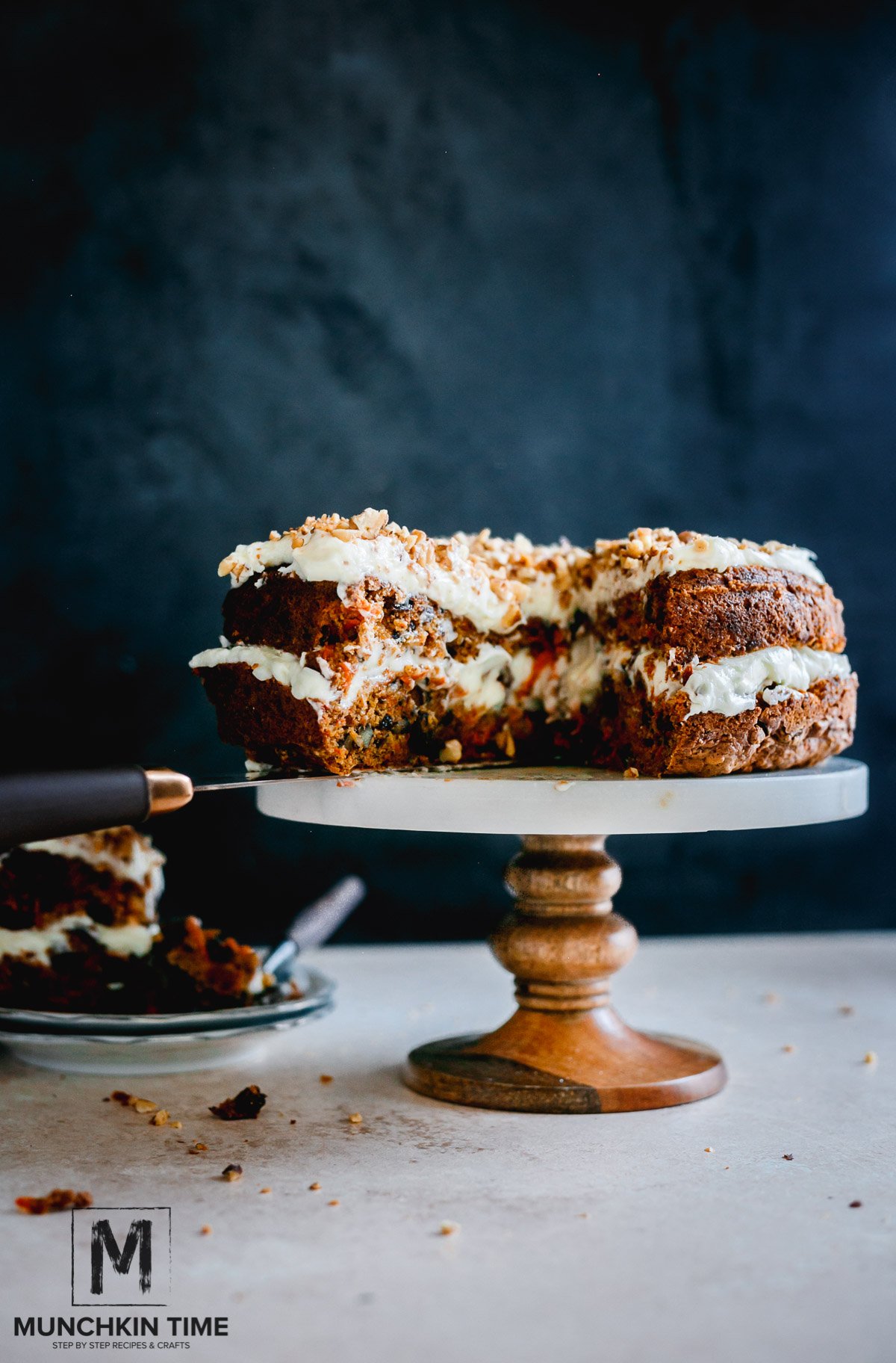 Best Carrot Cake Recipe From Scratch - a cut open carrot cake on a cake stand. Another slice on a plate next to the carrot cake.