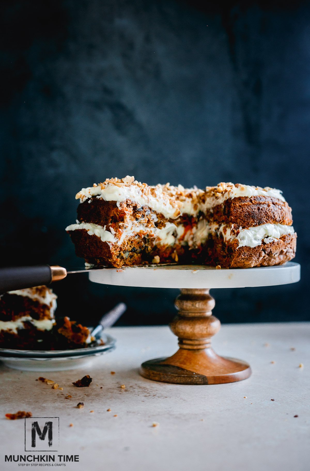 Best Carrot Cake Recipe From Scratch - a cut open carrot cake on a cake stand. Another slice on a plate next to the carrot cake.
