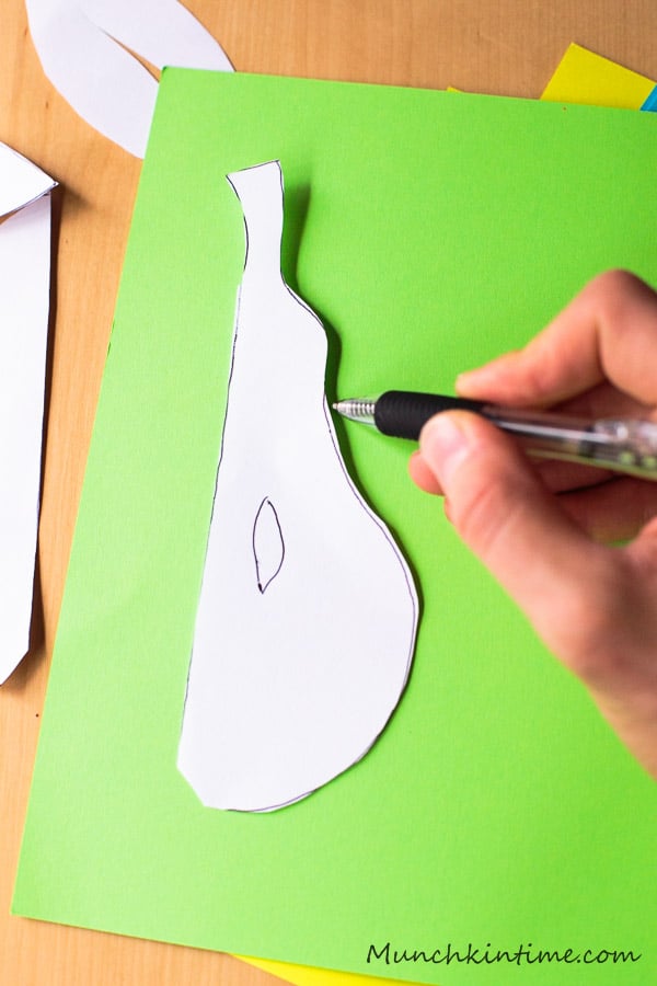 An outline half of the Paper Pear on a green construction paper.
