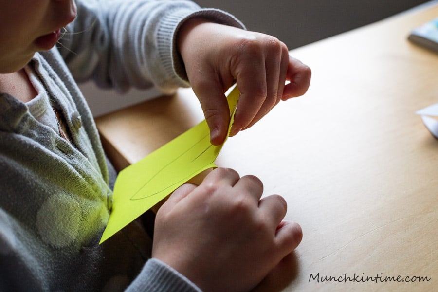 Easy construction paper craft for kids called Torn Paper Pear. A little girl holding paper in her hand.