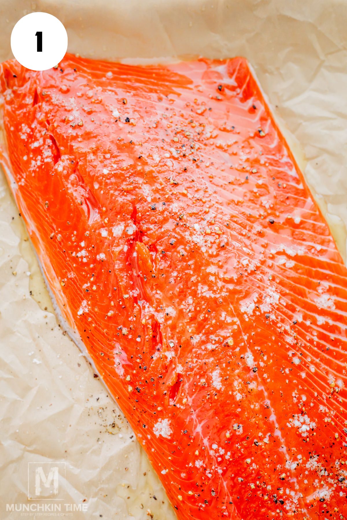 raw salmon on a baking sheet seasoned with salt and pepper.