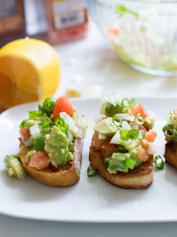 A plate with tomato bruschetta and ingredients on the side.