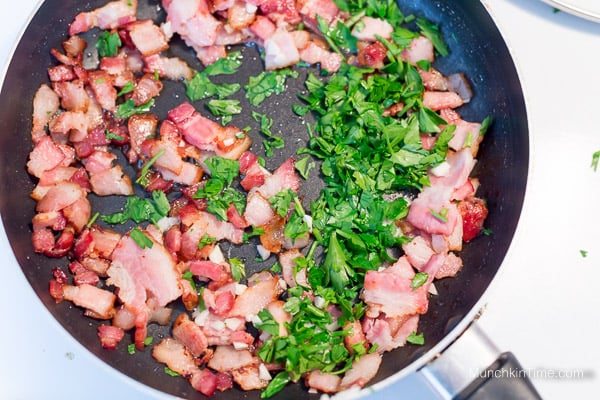 Cooked bacon with garlic and parsley inside the skillet.