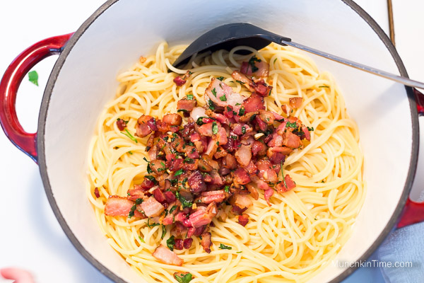 Pasta inside the bowl with bacon mixture.