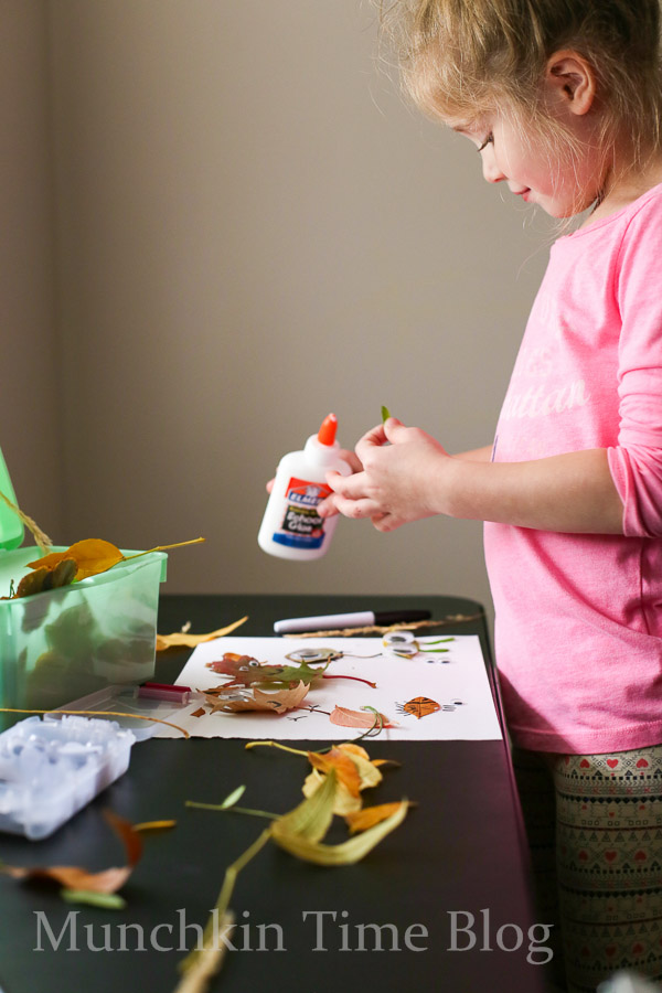 A little toddler crafting with fall leafs and a glue. 