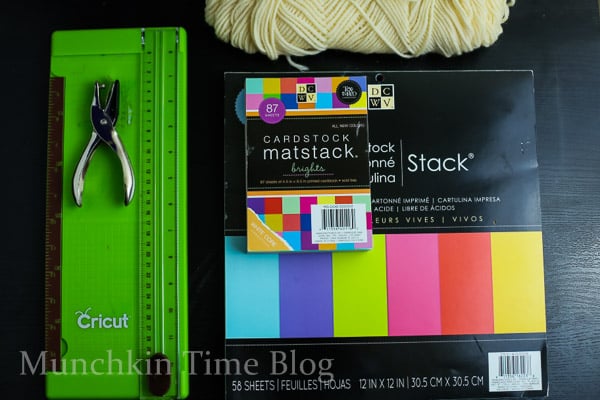 Construction paper, paper cutter, yarn and hole puncher.