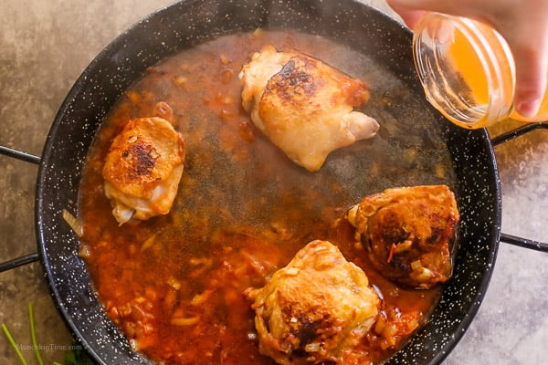 Chicken broth added into paella skillet. 