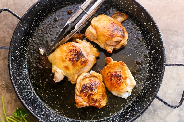 Fried chicken thighs inside paella skillet.