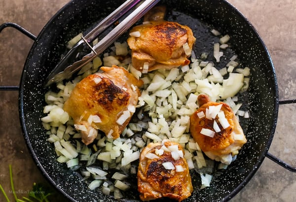 Fried chicken plus added chopped onion inside paella skillet.