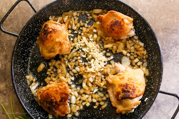 Saute onion with fried chicken plus added garlic inside paella skillet.