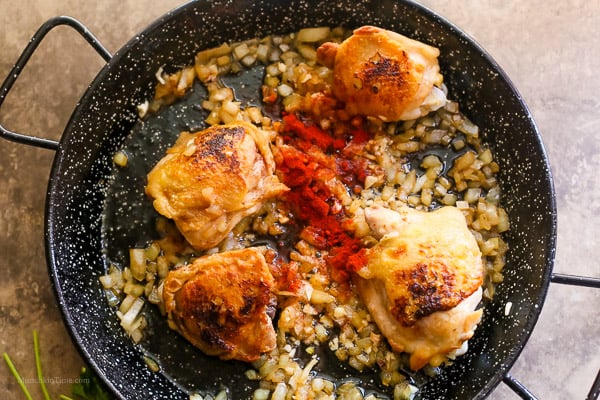 Paprika added into paella skillet.