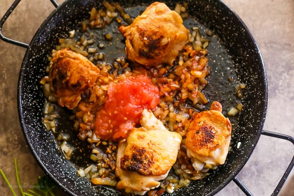 Chopped tomato added into paella skillet.