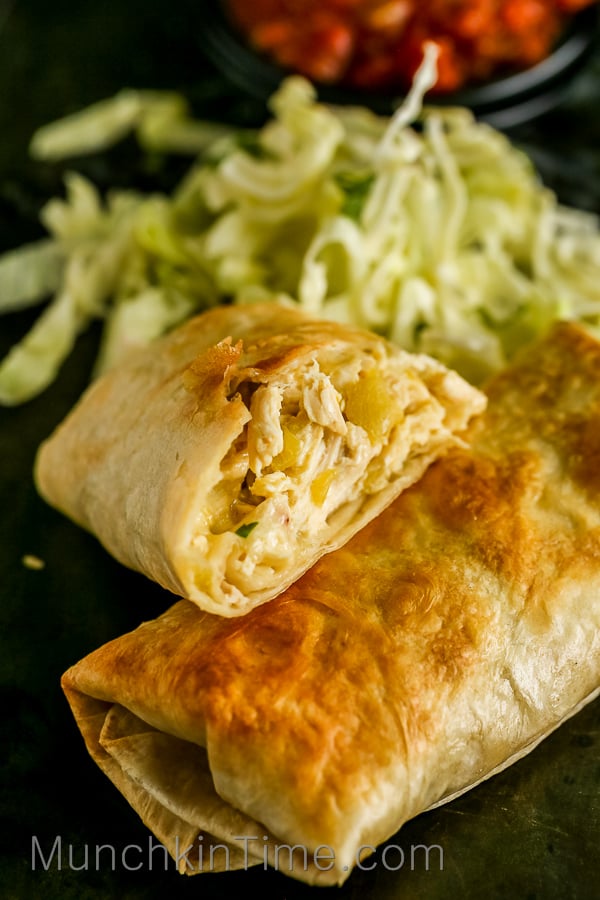 Chicken chimichanga cut open with chicken filling inside and a salad on a side.