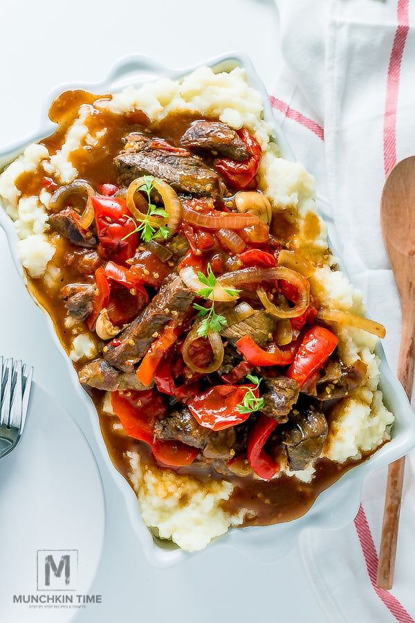 Pepper Steak served over mashed potatoes inside the casserole dish. 