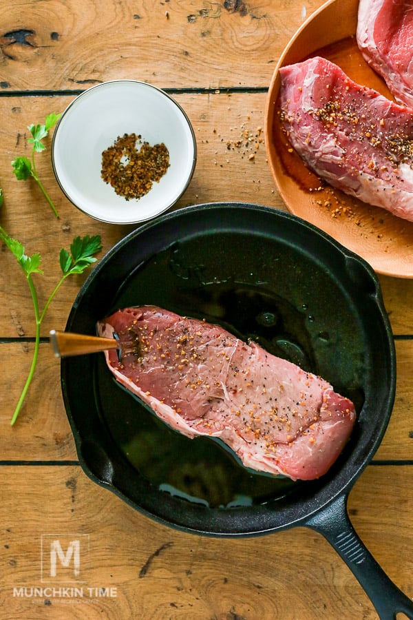 Steak seasoned with spices inside the cast iron skillet. 