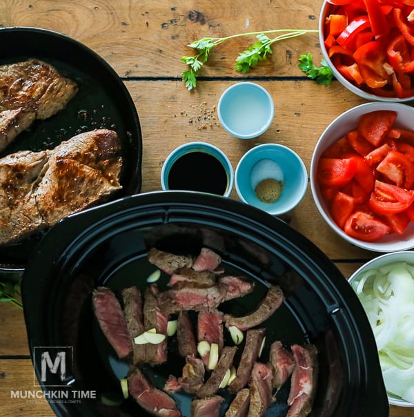 Fried Steak inside the slow cooker with tomatoes, bell pepper, onion, and seasonings.