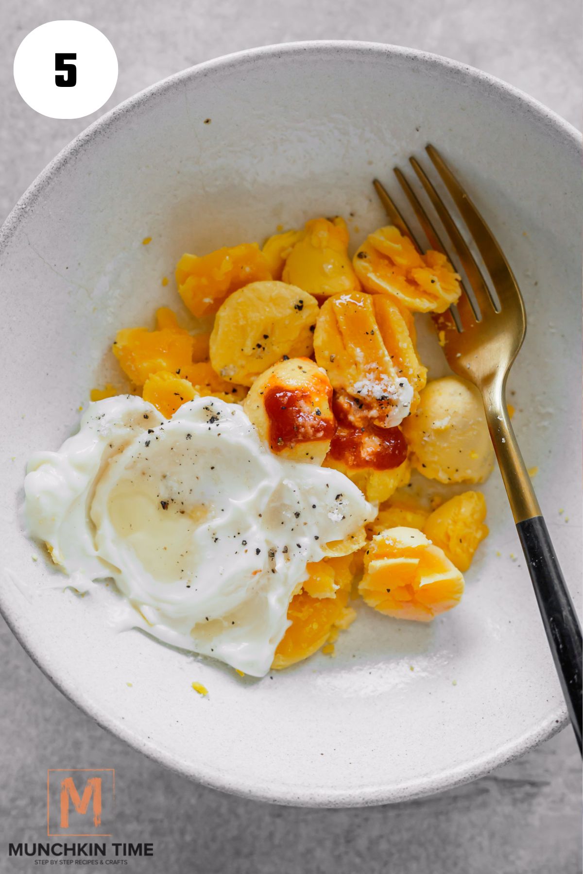 cooked egg yolks in a bowl with spices and mayo ready for mashing.