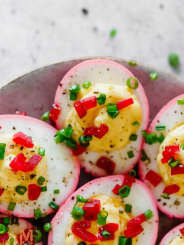 beet dyed deviled eggs with egg yolk filling and garnished with finely diced beets and chives.