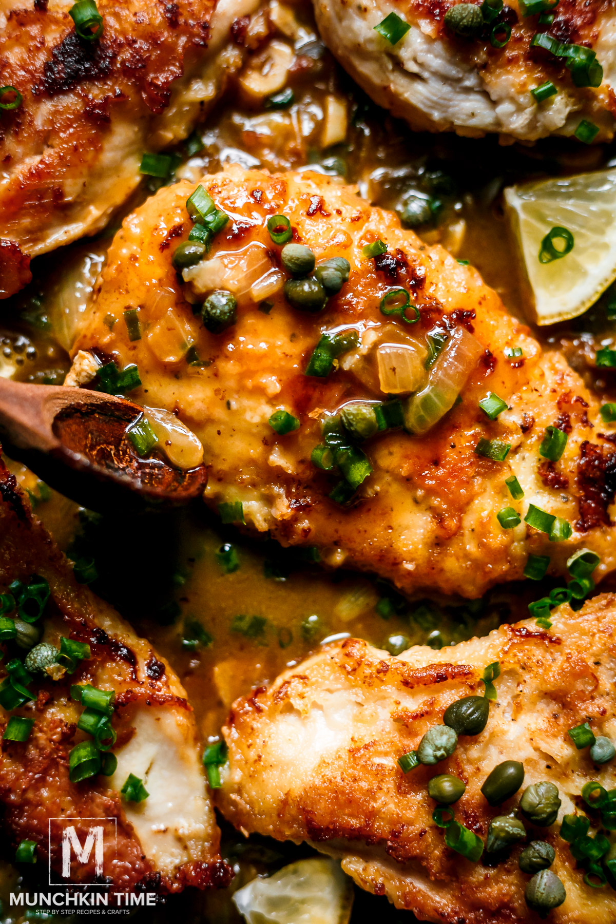 A close up shot of chicken piccata, capers, lemons and green onion.