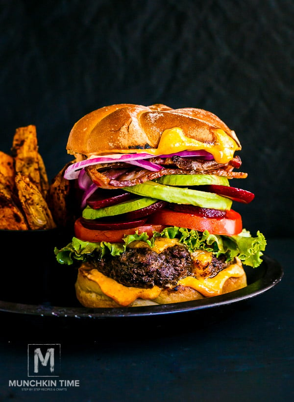 Best Hamburger Recipe - beef patties filled with cheddar cheese, served with lettuce, tomatoes, beets, avocado, bacon, red onion & a bun.