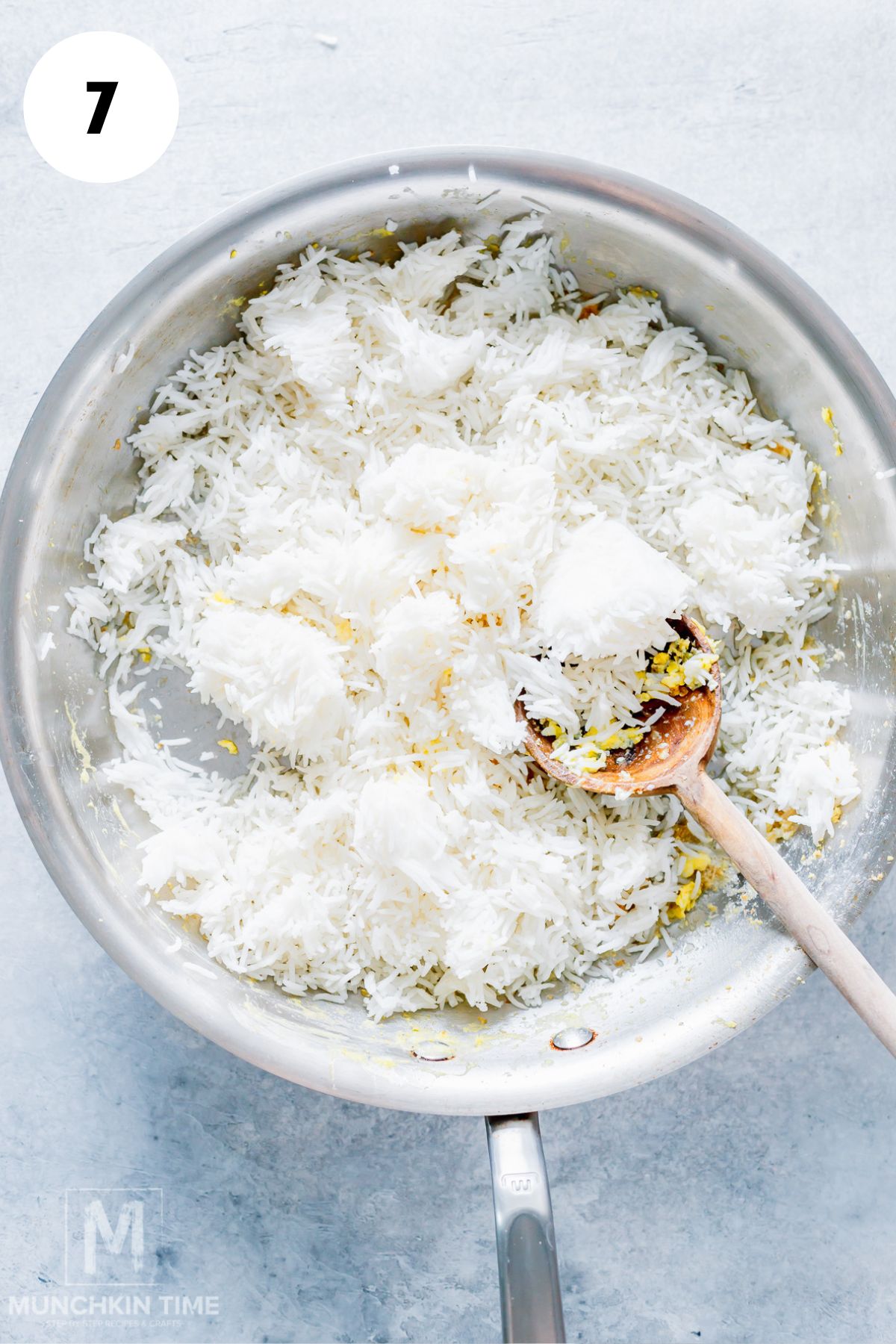 Adding cooked rice to the skillet to make homemade fried rice.