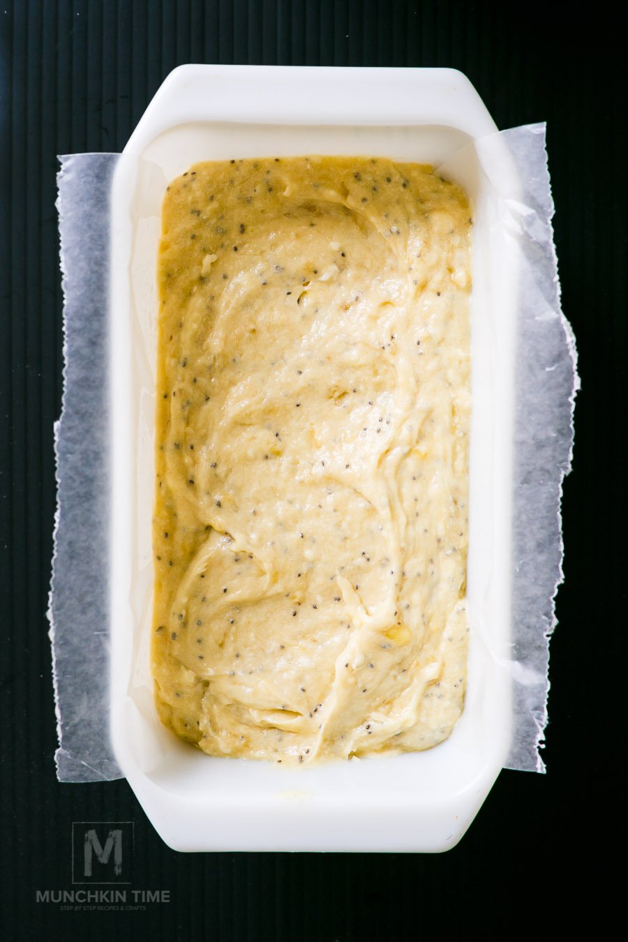 Banana bread batter inside baking pan lined with parchment paper. 