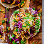 Tortillas with tender juicy pot roast beef and top with fresh homemade guacamole, cilantro, red cabbage, tomatoes and cheese.