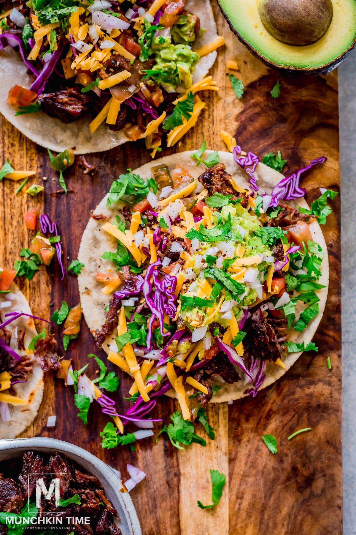 Tortillas with tender juicy pot roast beef and top with fresh homemade guacamole, cilantro, red cabbage, tomatoes and cheese.