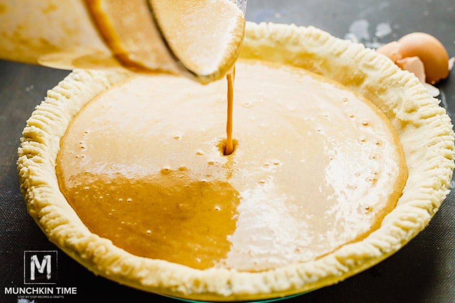 Gluten Free Pie Crust and pumpkin pie batter pouring into the crust. 