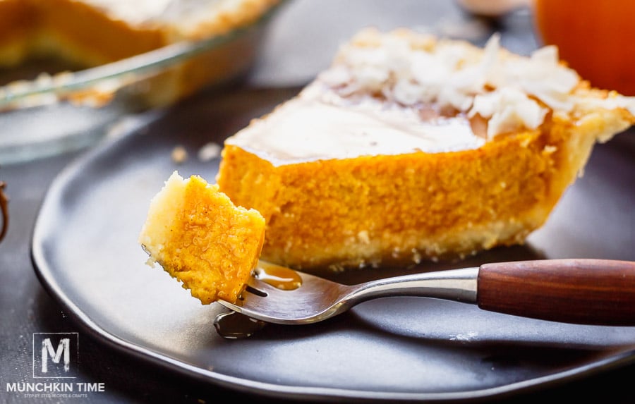 A slice of a pumpkin pie on a black plate. 