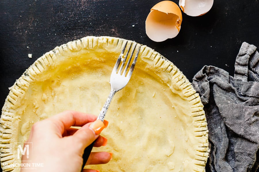 Pumpkin pie crust and a hand holding a fork.