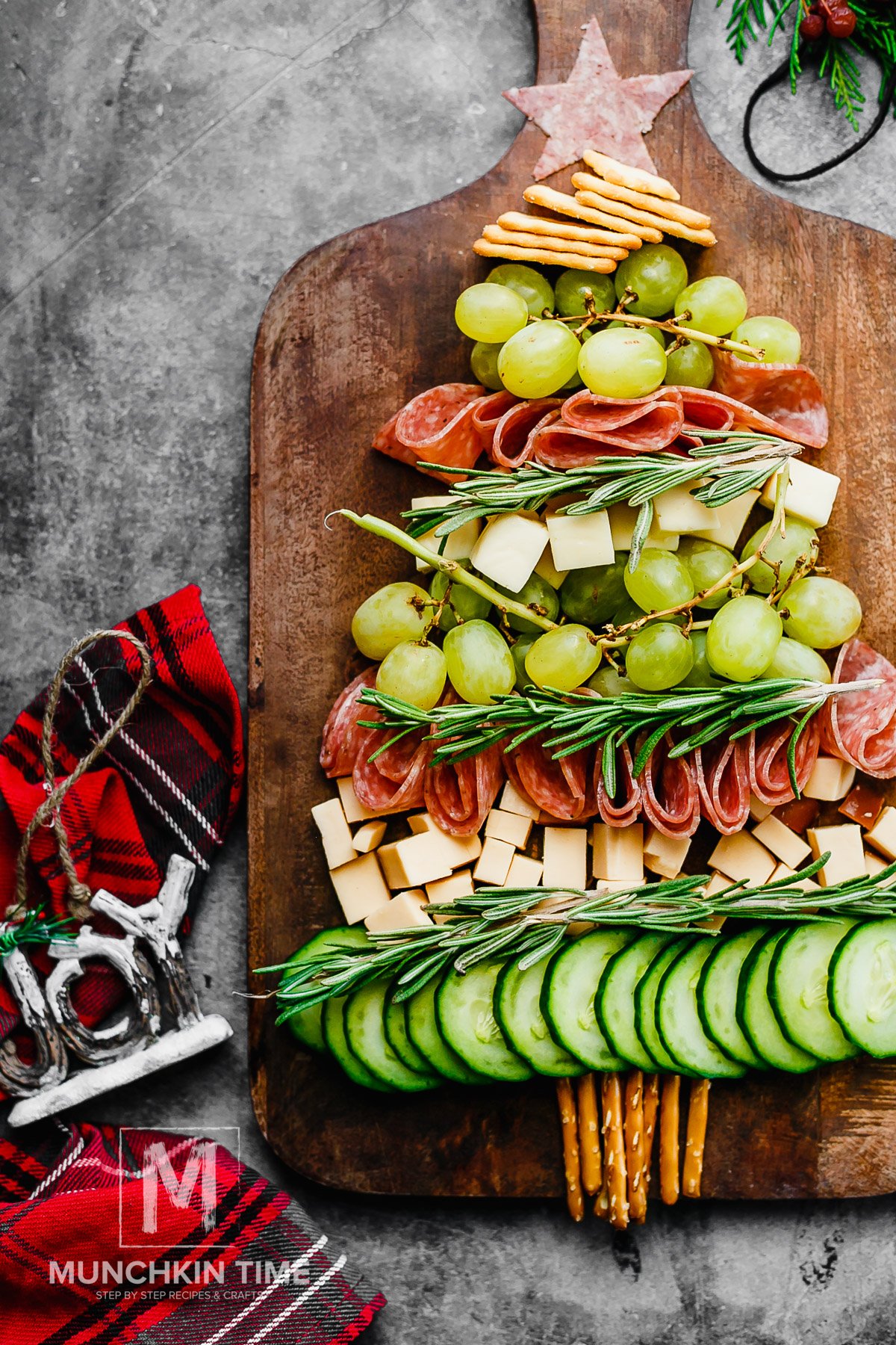 Christmas Tree Cheese Platter on a wooden board, made of cucumber, cheese, grapes and salami.