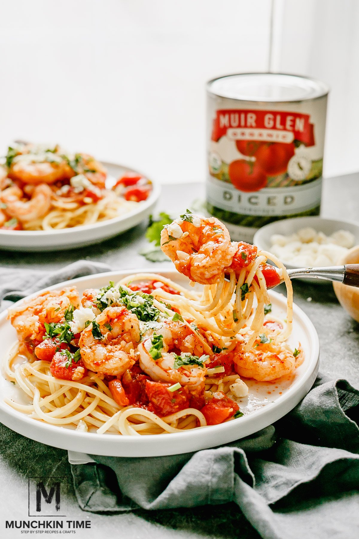 A close up shot of pasta. A fork filled with pasta, tomato pieces, shrimp and feta cheese.