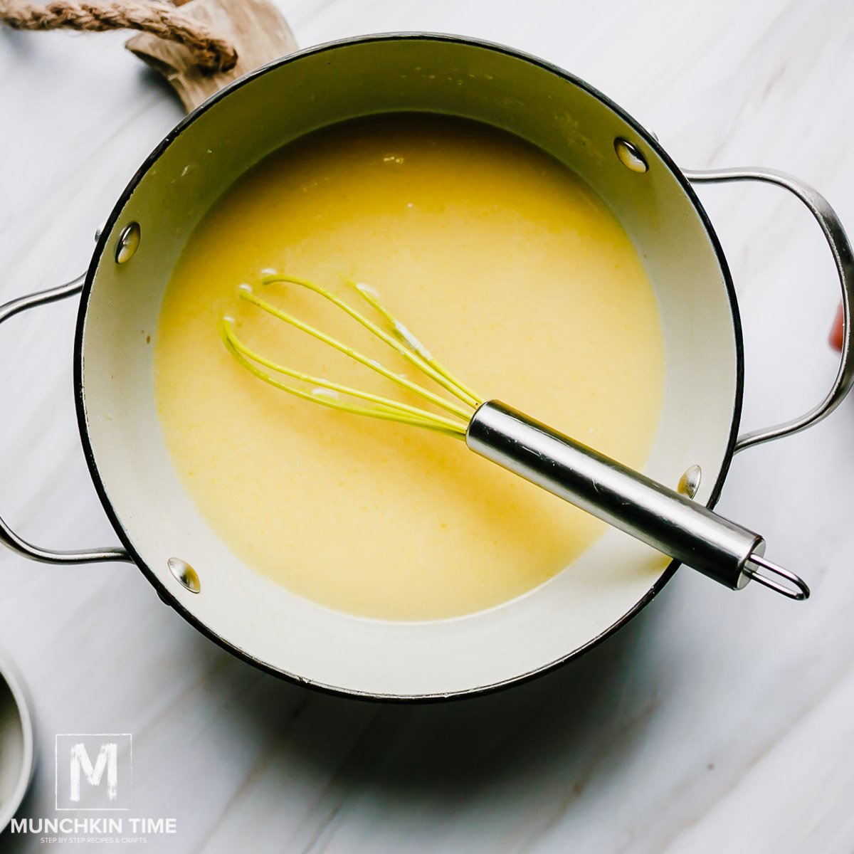 Sauce inside a sauce pot with a whisk. 