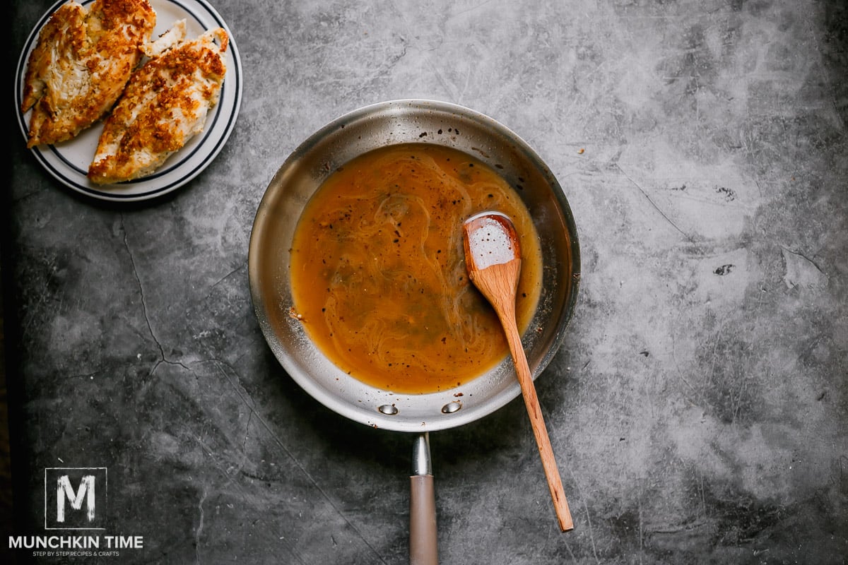 Chicken sauce inside the skillet with a wooden spoon.