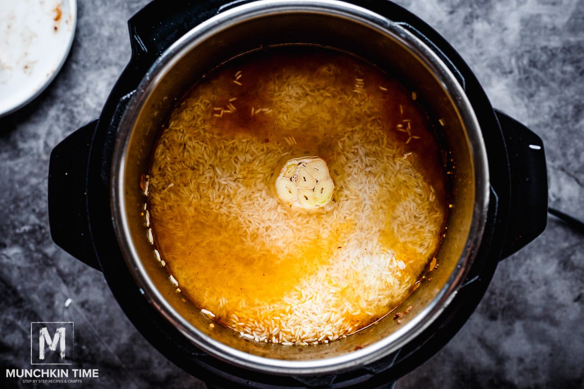 Open the lid then place rice over the meat, being careful not to mix it in too much, make sure to keep rice on top layer. Add 1 teaspoon of salt into 2Â½ cups of hot water and carefully pour it over the rice, be careful not to disturb the rice. Wiggle in 1 garlic head in the middle of the pot. Cover the Instant Pot and turn the valve to â€œSealingâ€. Cook on meat/stew setting for 5 minutes. After let it stand for 5 minutes before leasing the pressure.