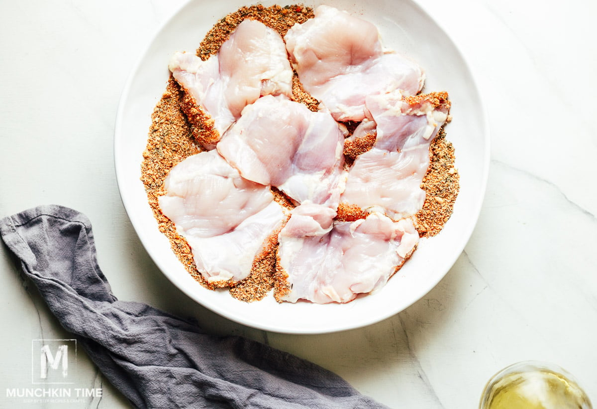 receita de coxas de frango sem pele assada no forno-passo dois: cubra as coxas de frango com a mistura de especiarias.