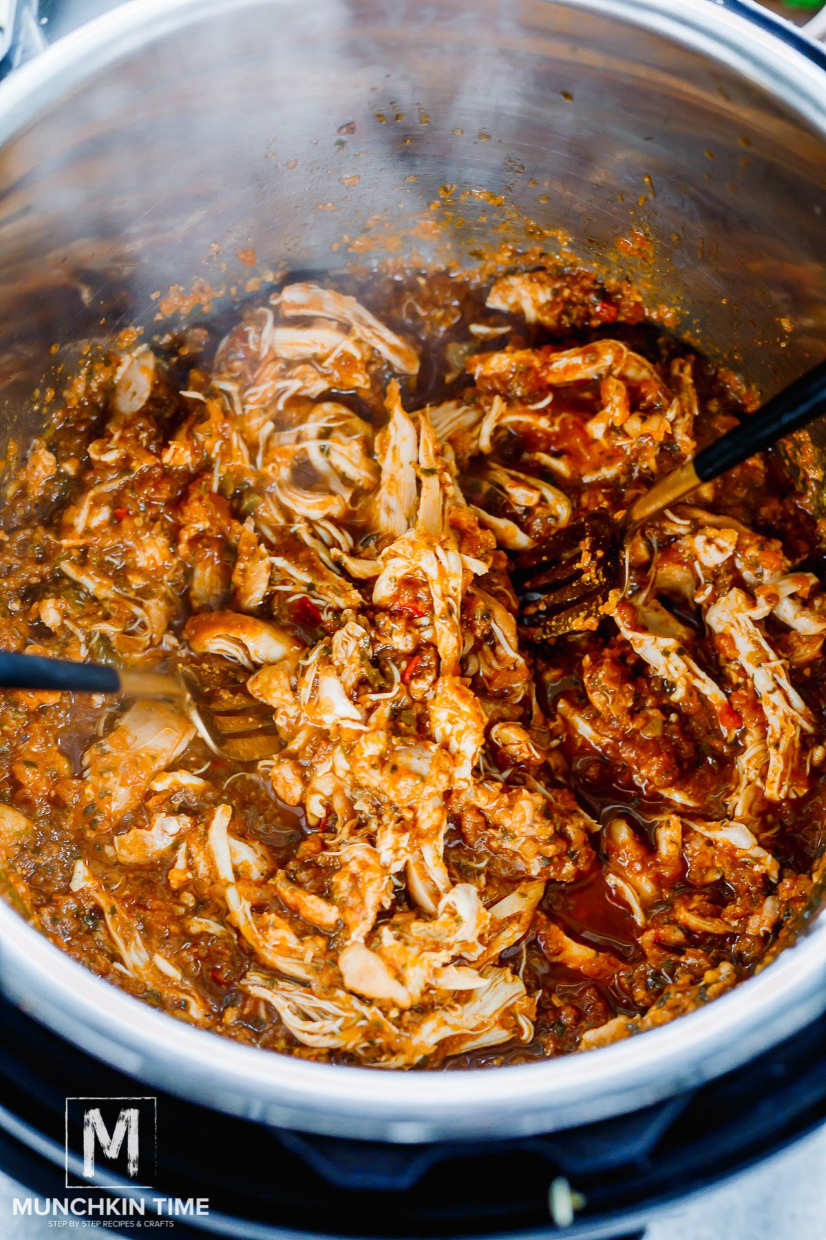 cooked chicken shredded with two forks inside the instant pot.