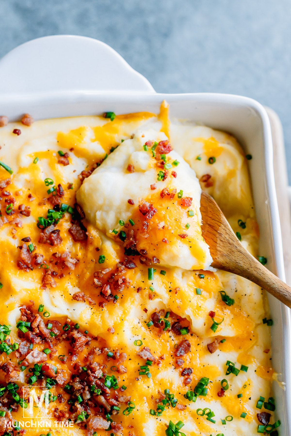 A scoop of baked mashed potato casserole garnish with cheese, bacon pieces and chives.