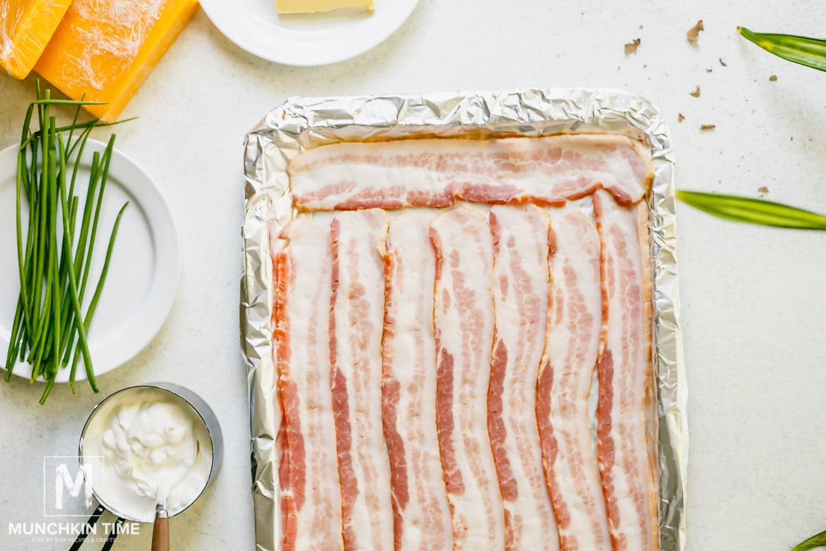 8 Slices of bacon on a baking sheet lied with foil paper, ready for baking.
