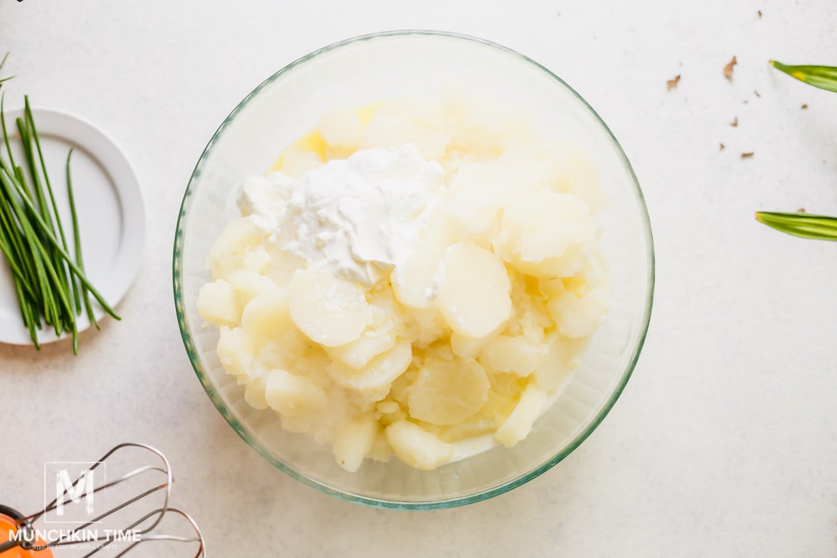 Cooked potato inside the mixing bowl with sour cream, milk and butter.