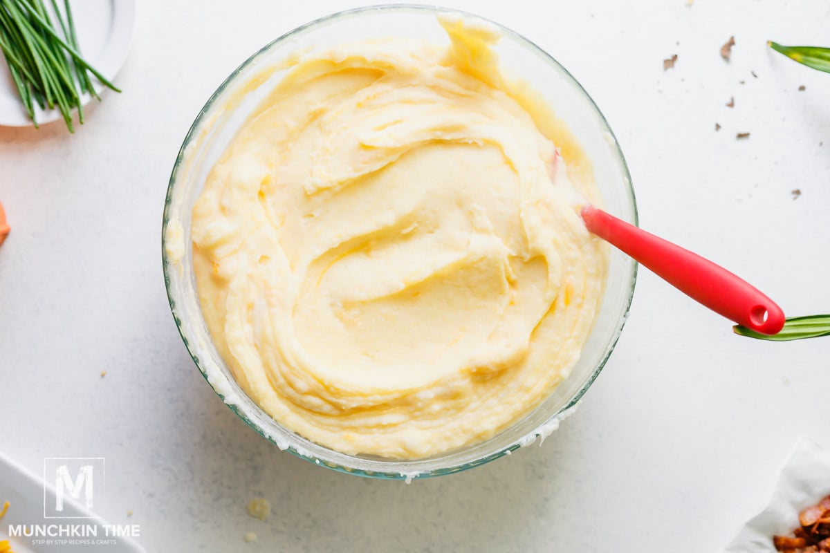 In a mixing bowl mashed potatoes mixing with cheese. 