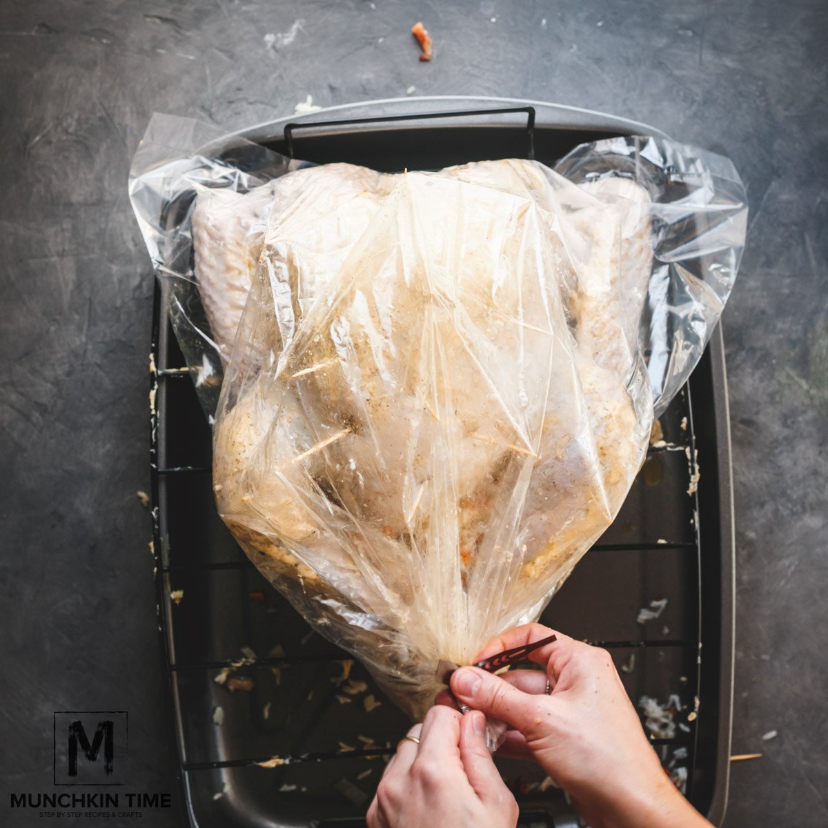 Toothpicks added to the top of the turkey, then turkey is being placed inside the greased baking bag.