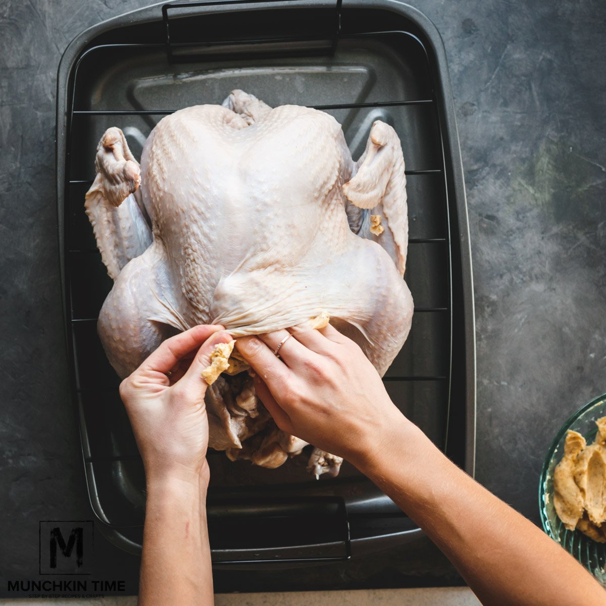 Seasoned butter being placed under the turkey skin.