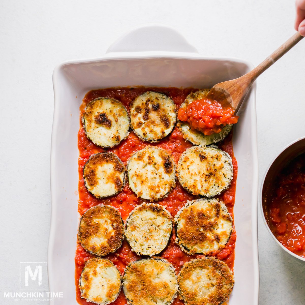 Eggplant topped with tomato sauce in the baking pan. 