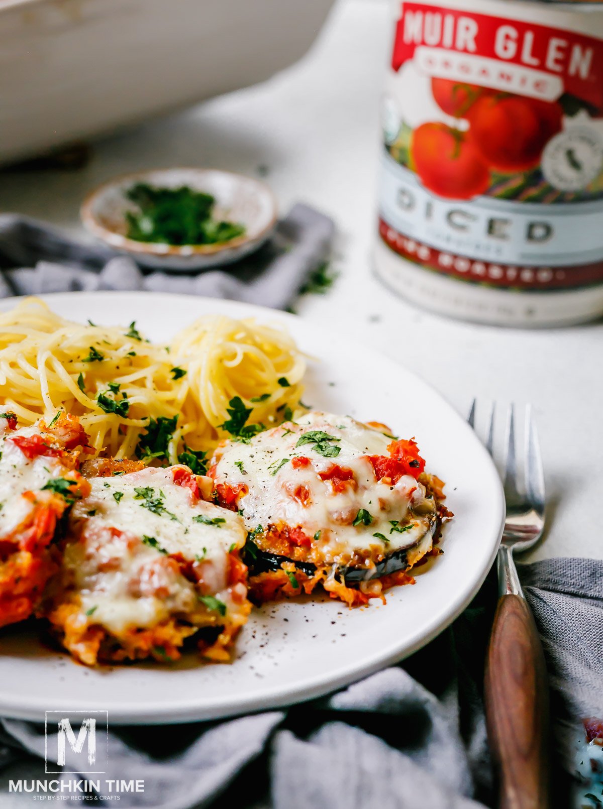 Baked Eggplant Parmesan on a plate with cooked pasta. 